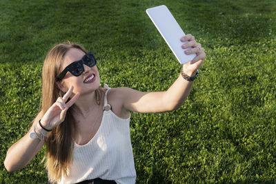 Portrait of a young woman using mobile phone on field
