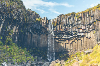 Scenic view of rock face and waterfall