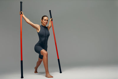 Low angle view of young woman exercising against clear sky