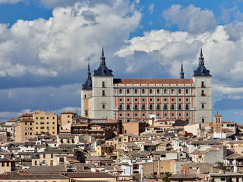 View of buildings in city against cloudy sky