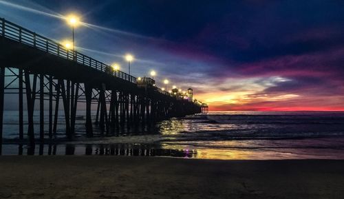 Pier over sea against sky at sunset