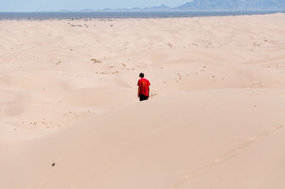 Teenage boy on desert against sky