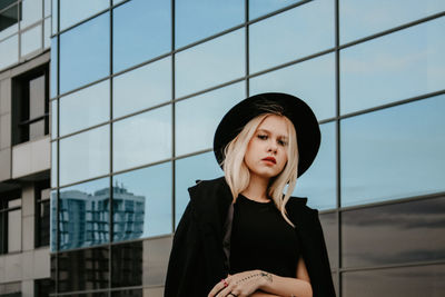 Portrait of young woman standing against buildings