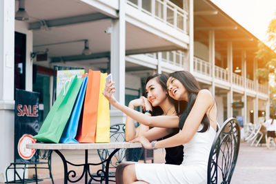 Female friends taking selfie while sitting at outdoor cafe