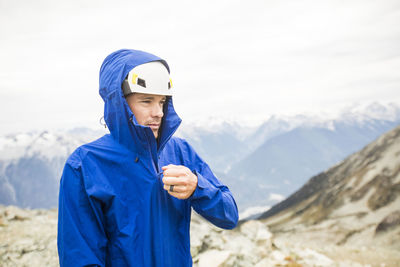 Portrait of mountain climber zipping up rain jacket.