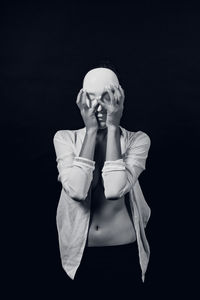 Young woman standing against black background