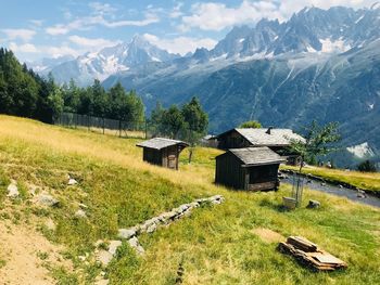 House on field by mountains against sky