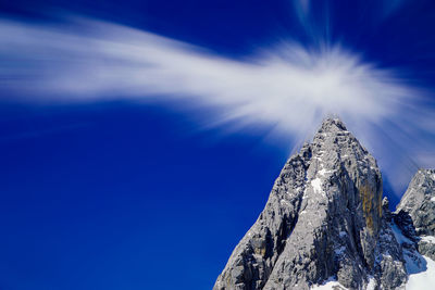 Low angle view of snowcapped mountain against blue sky