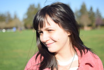 Close-up portrait of smiling young woman on field