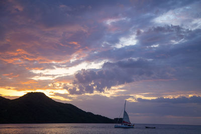 Sailboats in sea against dramatic sky