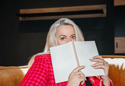 A sophisticated woman in a red textured jacket enjoys a captivating read