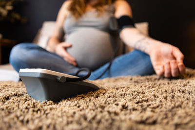 Low section of woman sitting on rug at home