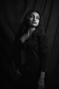 Young woman standing against curtain