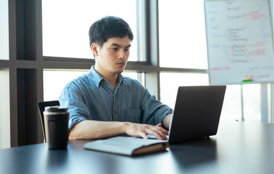 Young man using laptop at desk in office