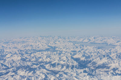 Aerial view of snowcapped landscape against clear blue sky