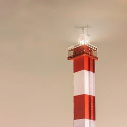 Low angle view of lighthouse against building against sky