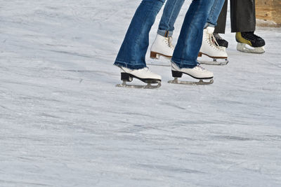 Low section of people ice-skating on ice rink during winter