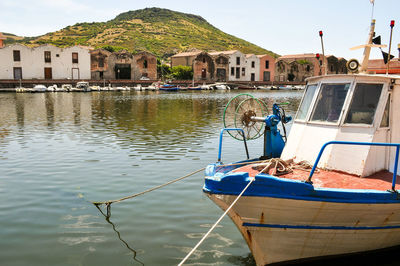 Boats moored on sea by mountain against sky