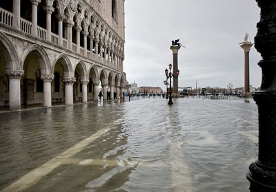 Water filled walkway by doges palace against sky