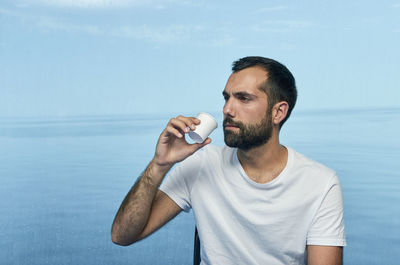 Man holding drink standing by water