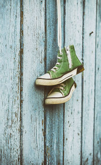 Green shoes hanging on wooden wall