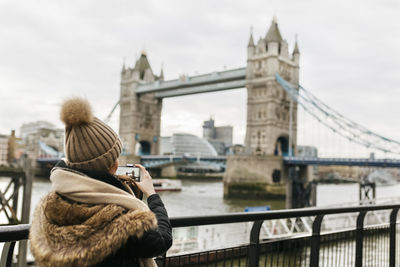 Uk, london, back view of young woman taking picture of tower of london