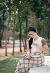 Woman having drink while reading book at public park