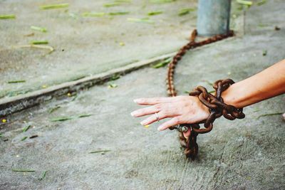Cropped hand of woman locked in rusty metallic chain