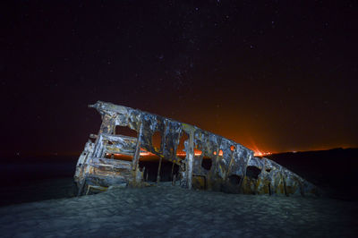 Shipwreck at beach against sky during night