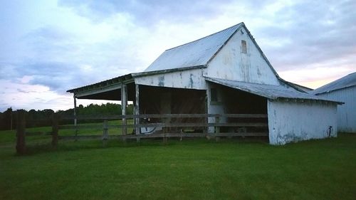 Barn on grassy field against cloudy sky