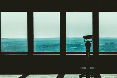 Silhouette against sky seen through window