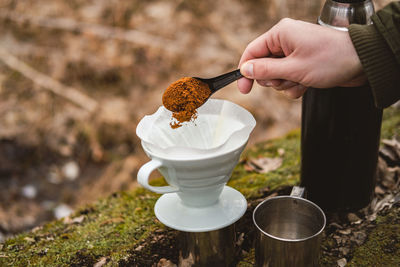 Making pour over coffee outdoors at a hiking trip. hand pouring ground coffee into a paper filter