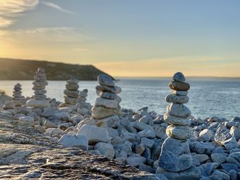 Stack of stones on beach against sky during sunset