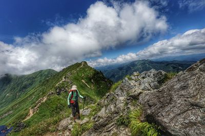 Rear view of woman standing on mountain against sky