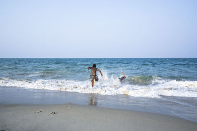 Men on beach against clear sky