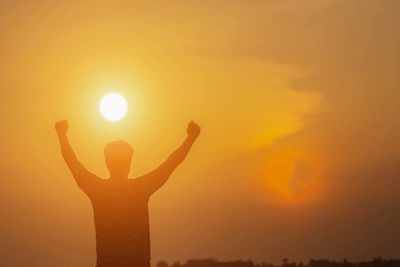 Silhouette person standing against orange sky during sunset