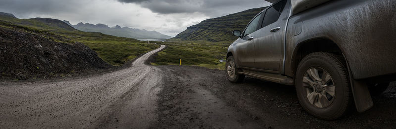 Dirt road by mountains against sky