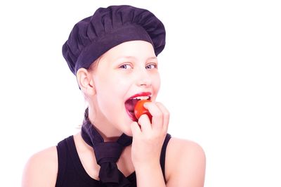 Portrait of young woman eating food against white background