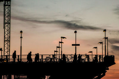 Silhouette people standing by railing against sky during sunset