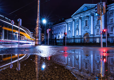 Reflection of buildings in puddle at night