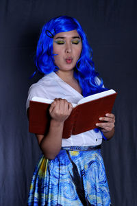 Midsection of woman reading book against black background