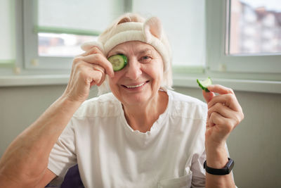 Mature woman covers eyes with cucumber and enjoys life at home, wellness and beauty care at any age