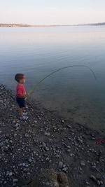 Boy on sea shore against sky