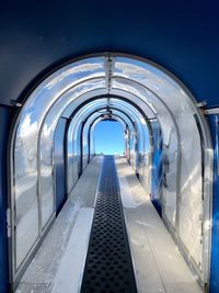 Empty corridor in building against clear blue sky