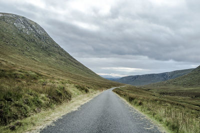Country road against cloudy sky