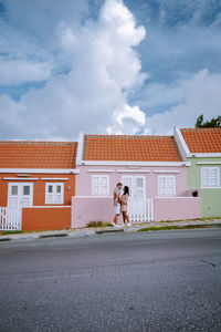 Woman standing by road against building