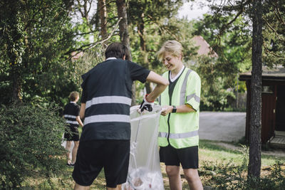 Happy soccer boys collecting plastic in garbage bag