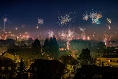 Firework display in city against sky at night