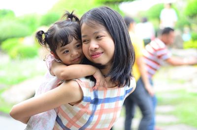 Mother carrying daughter on back outdoors