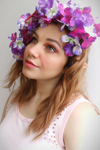 Portrait of beautiful woman with flower crown against wall